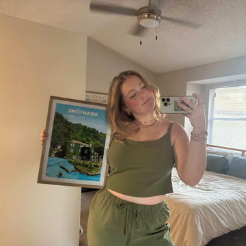 Woman holding a framed picture in a bedroom