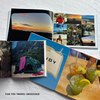 Open photo album with travel-themed images and a wooden table with various photos.