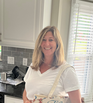 A smiling woman stands in a kitchen.