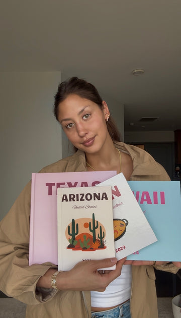 Person holding books titled 'Texas', 'Arizona', and 'Hawaii' with colorful covers.
