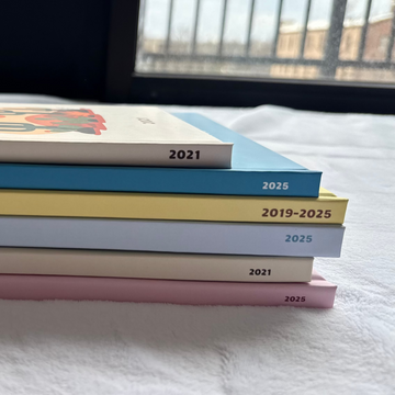 Stack of travel photobooks on a bed with a window in the background
