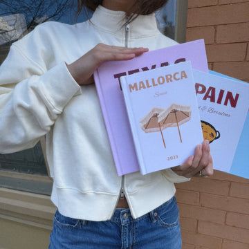 Person holding three books with visible text and graphics.