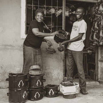 Two people posing for a photo, holding a small grill