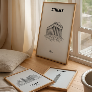 Framed prints of famous landmarks on a wooden surface with a window in the background
