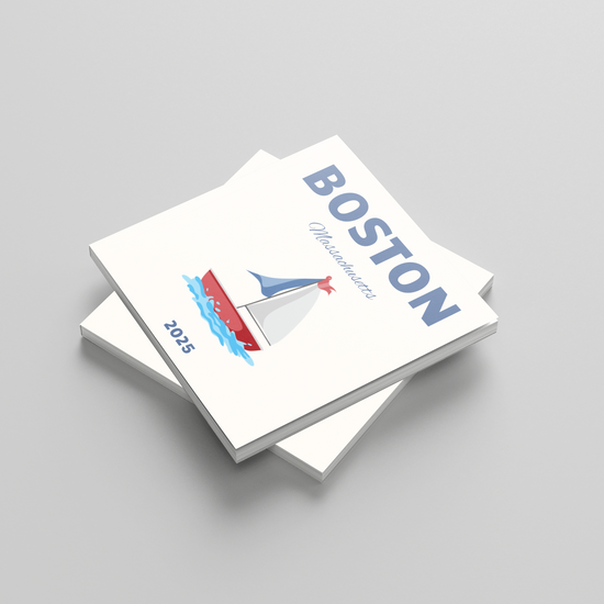 Stack of photobooks with 'Boston' and sailboat illustration on a gray background