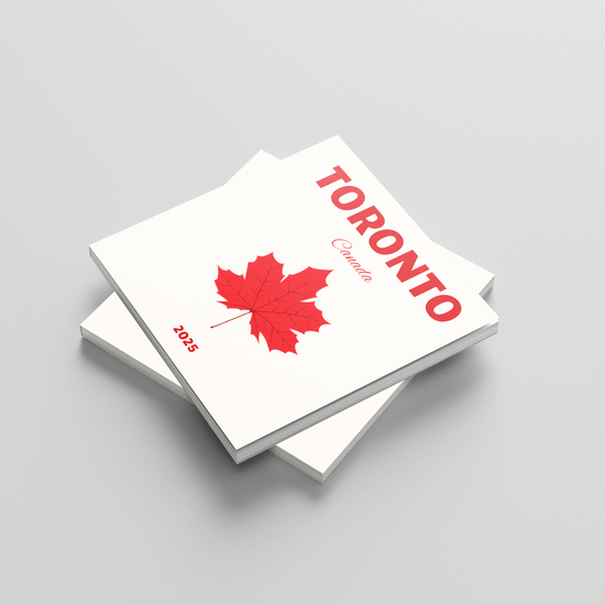 Stack of square photobooks with a red maple leaf and 'Toronto' text on a gray background