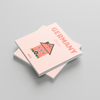 Two pink square photobooks with a house illustration and 'Germany' text on a gray background