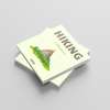 Two square photobooks stacked on a light gray background, with one notebook showing a hiking illustration and the other displaying 'Hiking 2025'.
