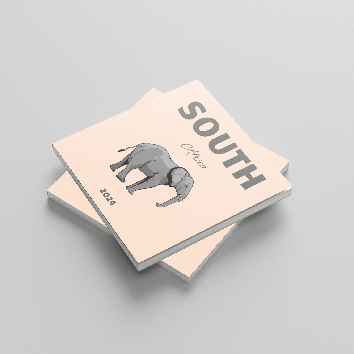 Two square photobooks stacked on a light gray background, with one book showing an elephant illustration and displaying text of 'South Africa'