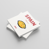 Stack of white square photobooks with a colorful illustration and 'SPAIN' text on a light gray background