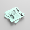 Stack of books with 'Thailand' and a map on the cover against a light gray background